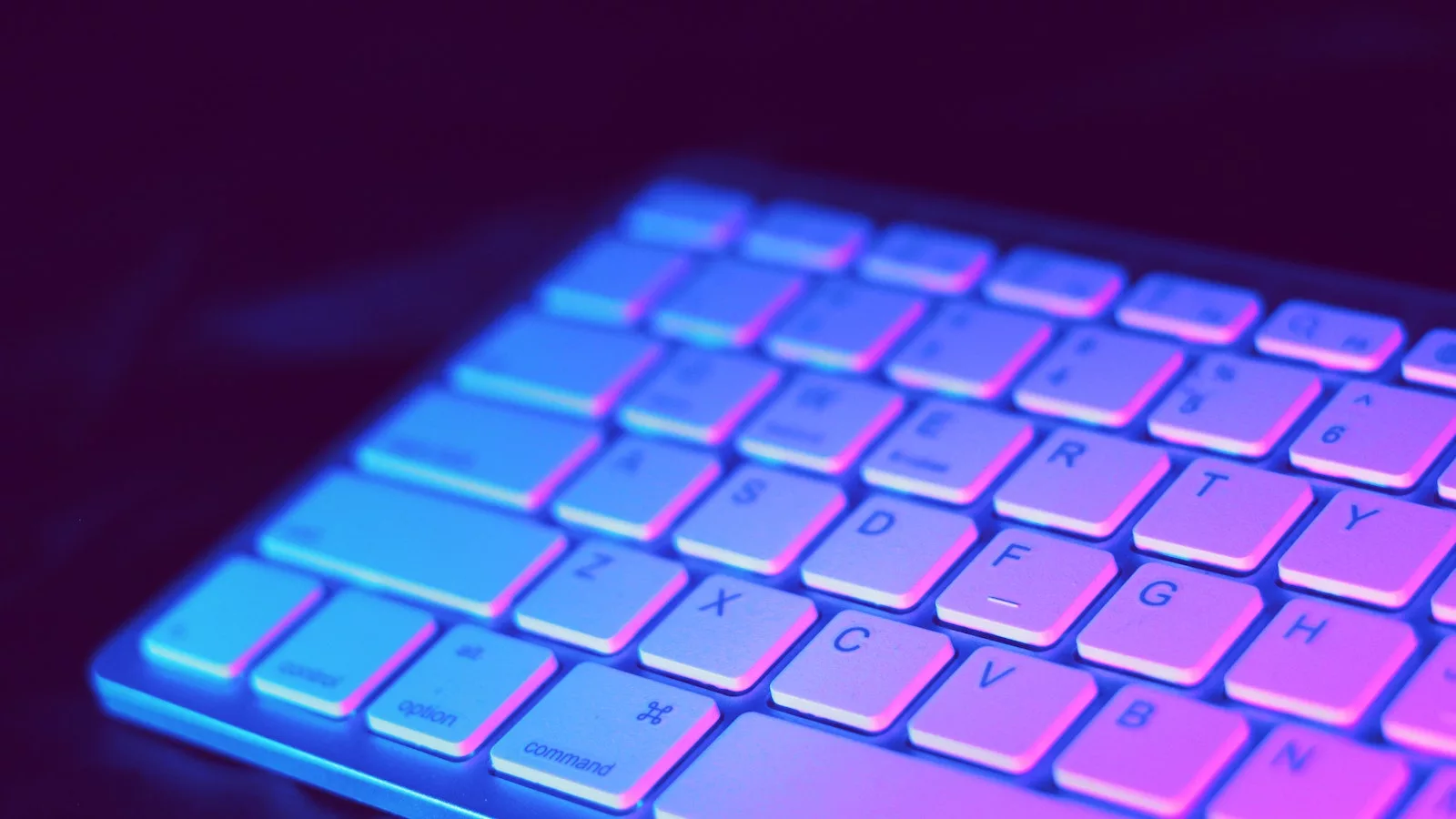 mac keyboard lit by purple light